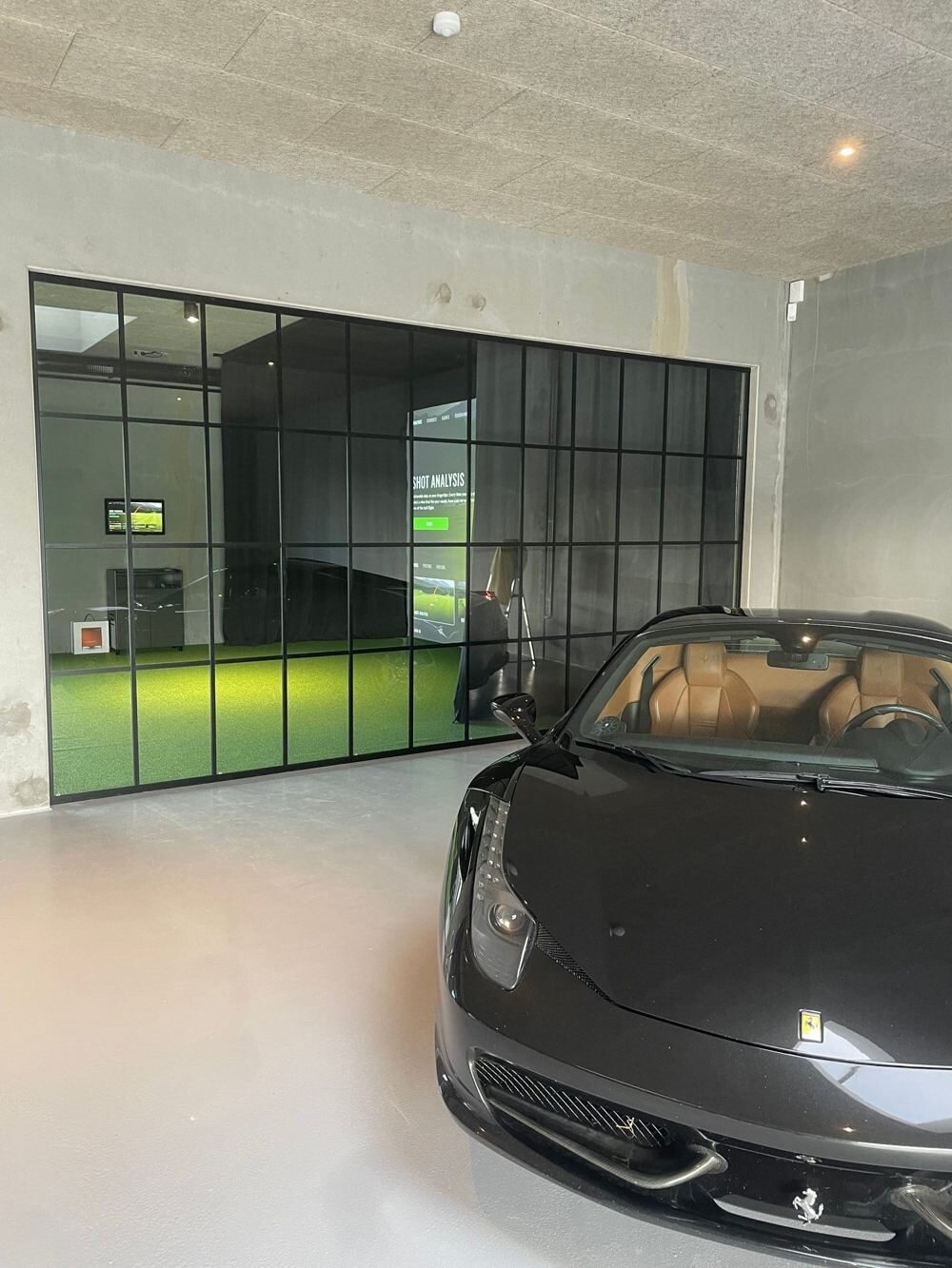 Glass fronted private simulator room beside a car collection